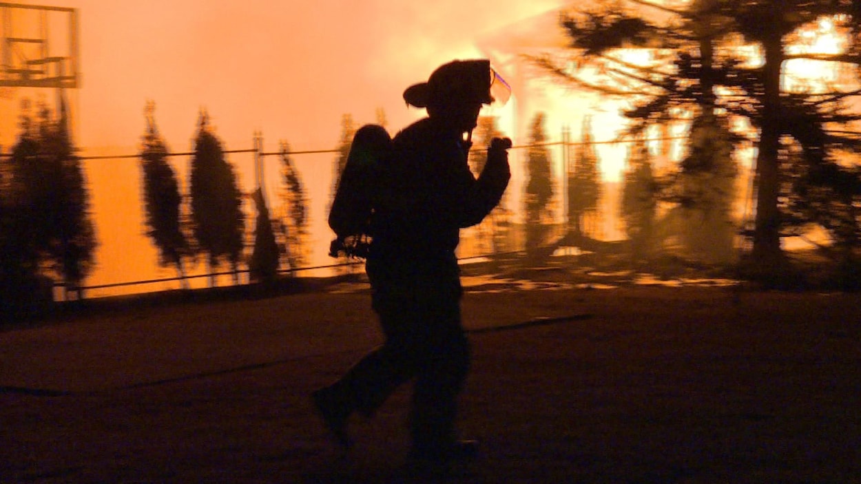 Photo d'un pompier avec un ciel rougi par les flammes en arrière-plan. Photo d'un pompier avec un ciel rougi par les flammes en arrière-plan.