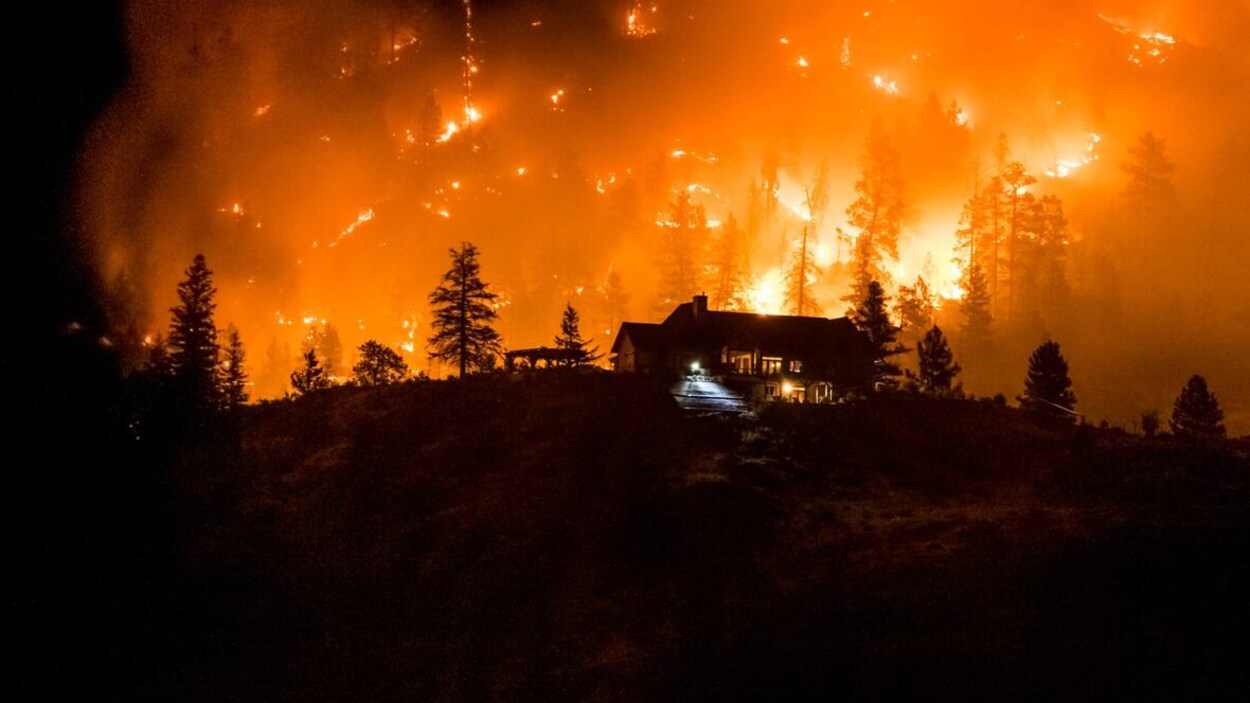 Une maison du quartier Heritage Hills avec à l'arrière les flammes du feu de forêt.