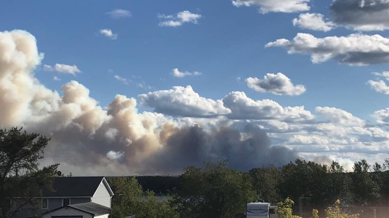 De la fumée derrière le toit d'une maison
