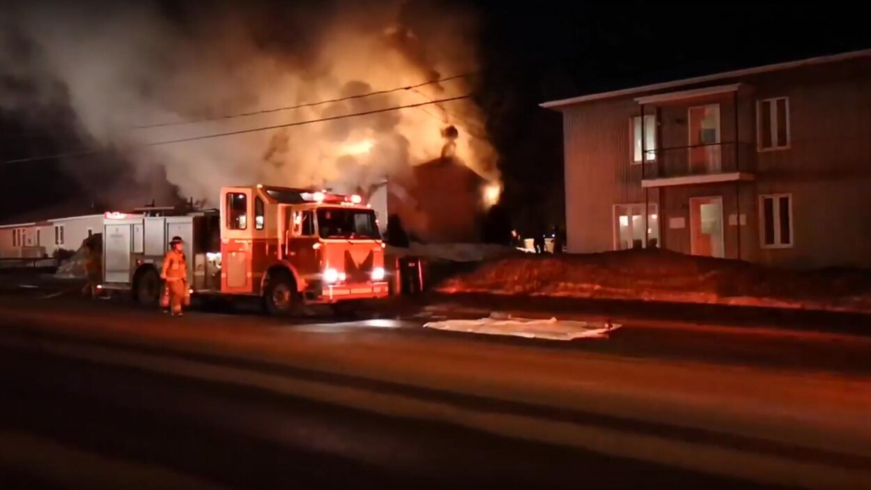 Des camions de pompiers devant une maison en feu