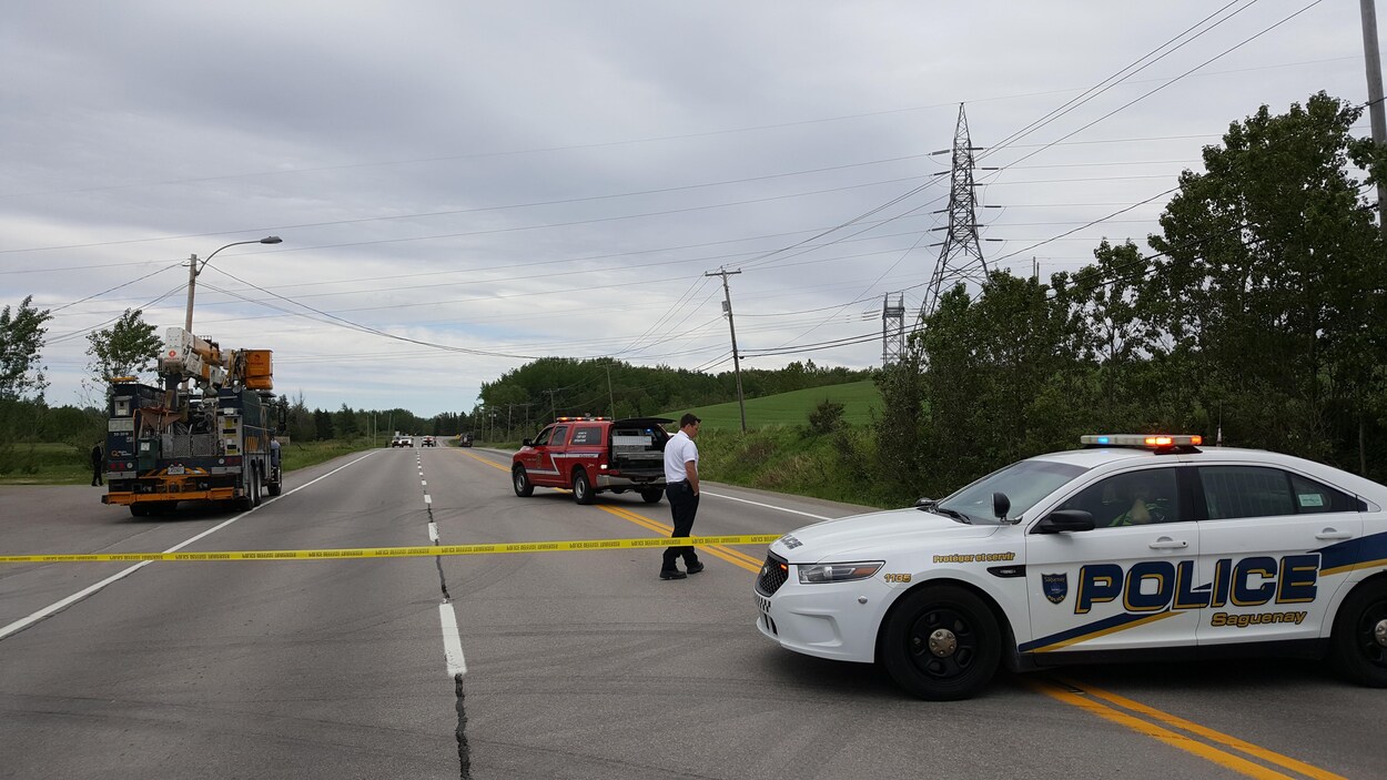 Un véhicule de police bloque la route. Il y a un véhicule du service incendie et un véhicule d'Hydro Québec. Un véhicule de police bloque la route. Il y a un véhicule du service incendie et un véhicule d'Hydro Québec.