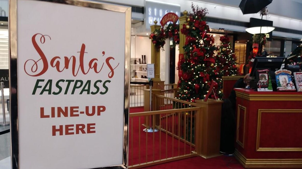 L'entrée du village du père Noël d'un centre commercial arbore une affiche indiquant, en anglais, l'entrée de la file d'attente rapide Santa's FastPass.