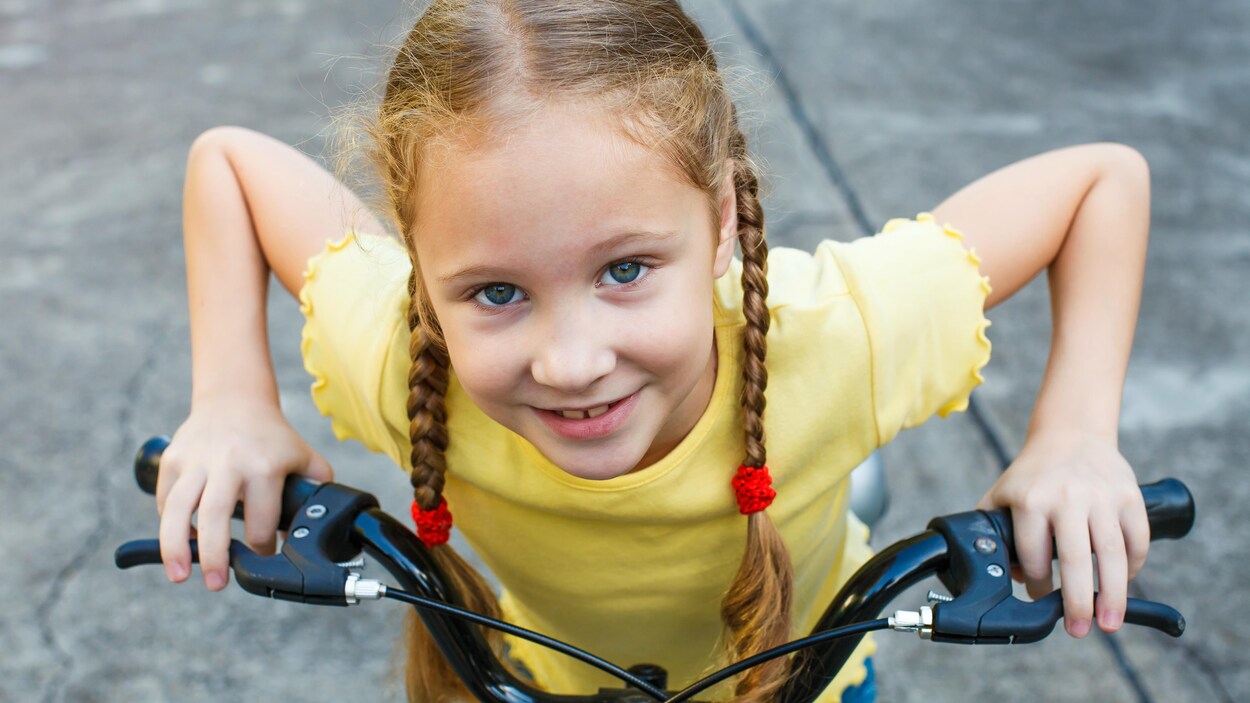 Une jeune fille fait du vélo.