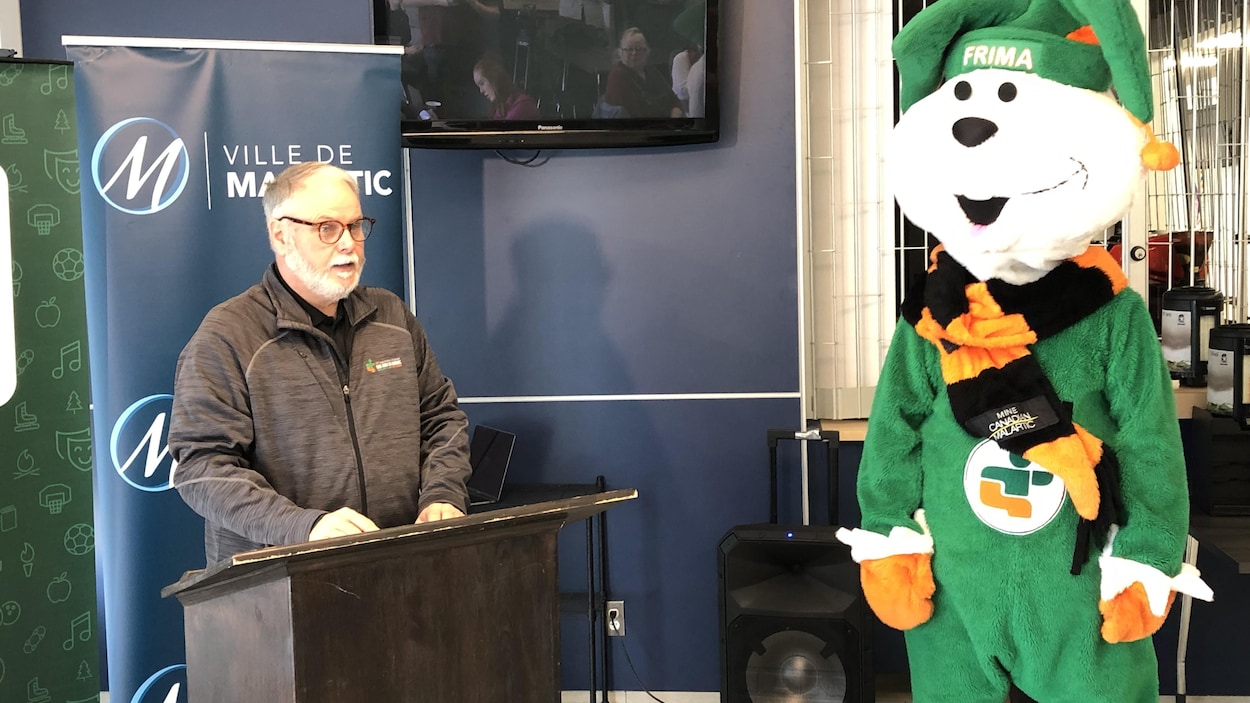 Un homme parle aux lutrins, une mascotte des Jeux du Québec en Abitibi-Témiscamingue à ses côtés.