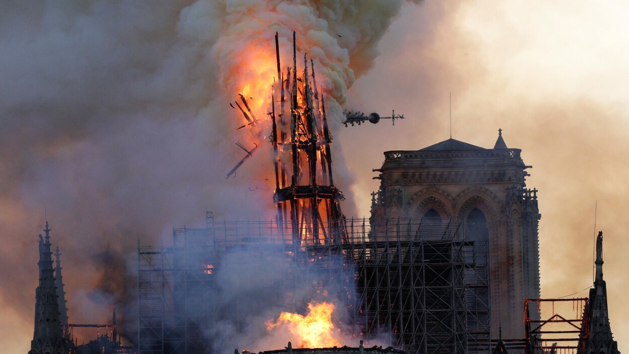 La flèche de la cathédrale, en feu, commence à s'écrouler.