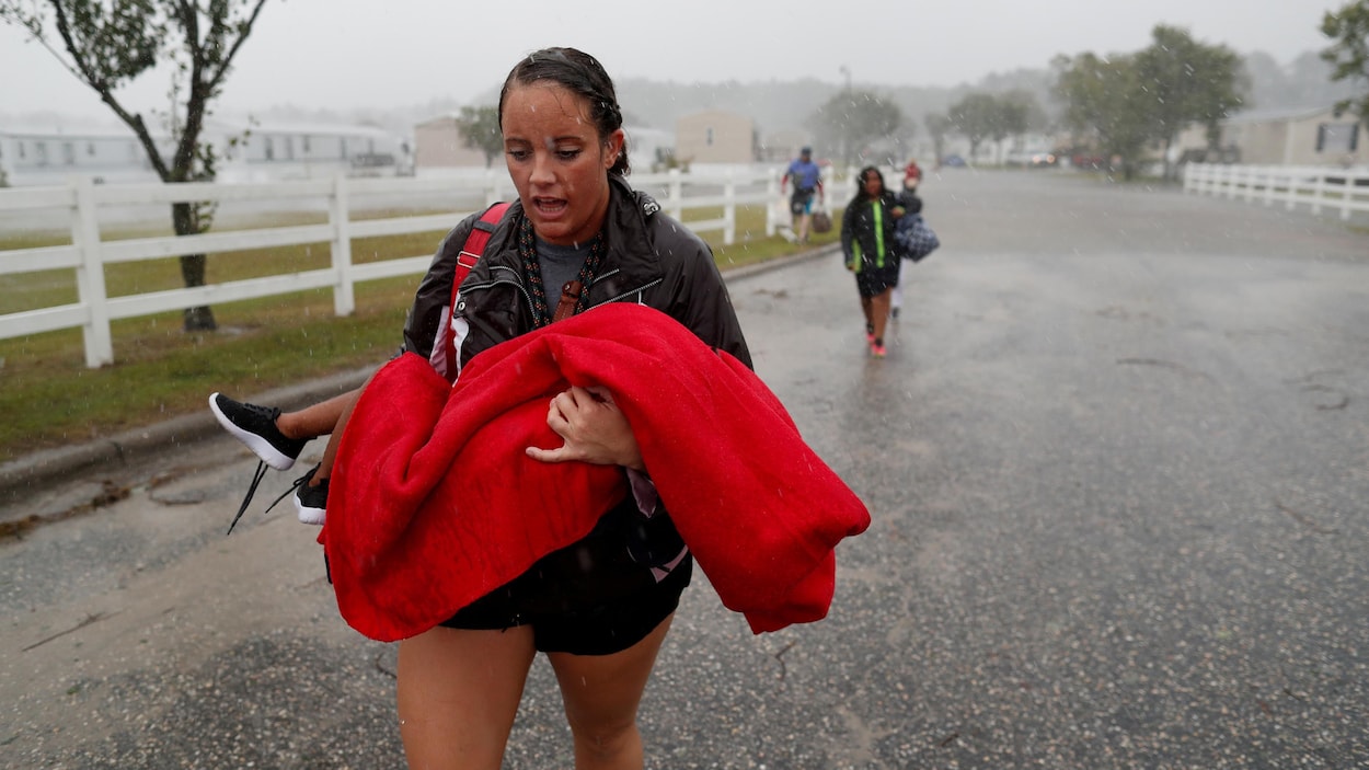Une femme transporte un enfant évacué, le tout sous une pluie battante. Une femme transporte un enfant évacué, le tout sous une pluie battante.
