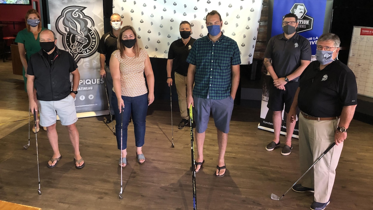 Huit membres de la Fondation portent des masques et tiennent chacun un bateau de golf.