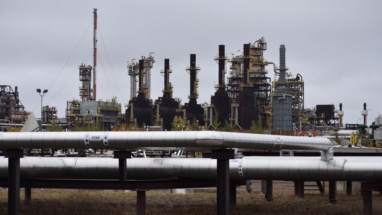 Des tuyaux gris devant des installations pétrolières. Des tuyaux gris devant des installations pétrolières.