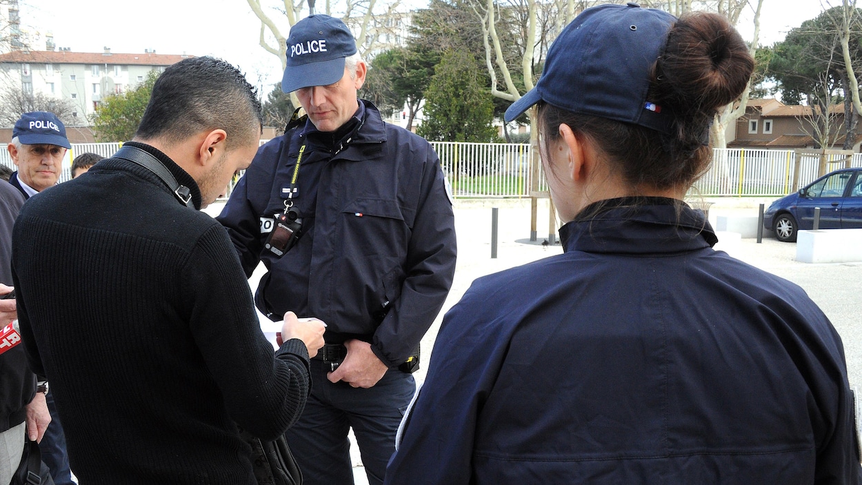 Deux policiers regardent les papiers d'un homme.