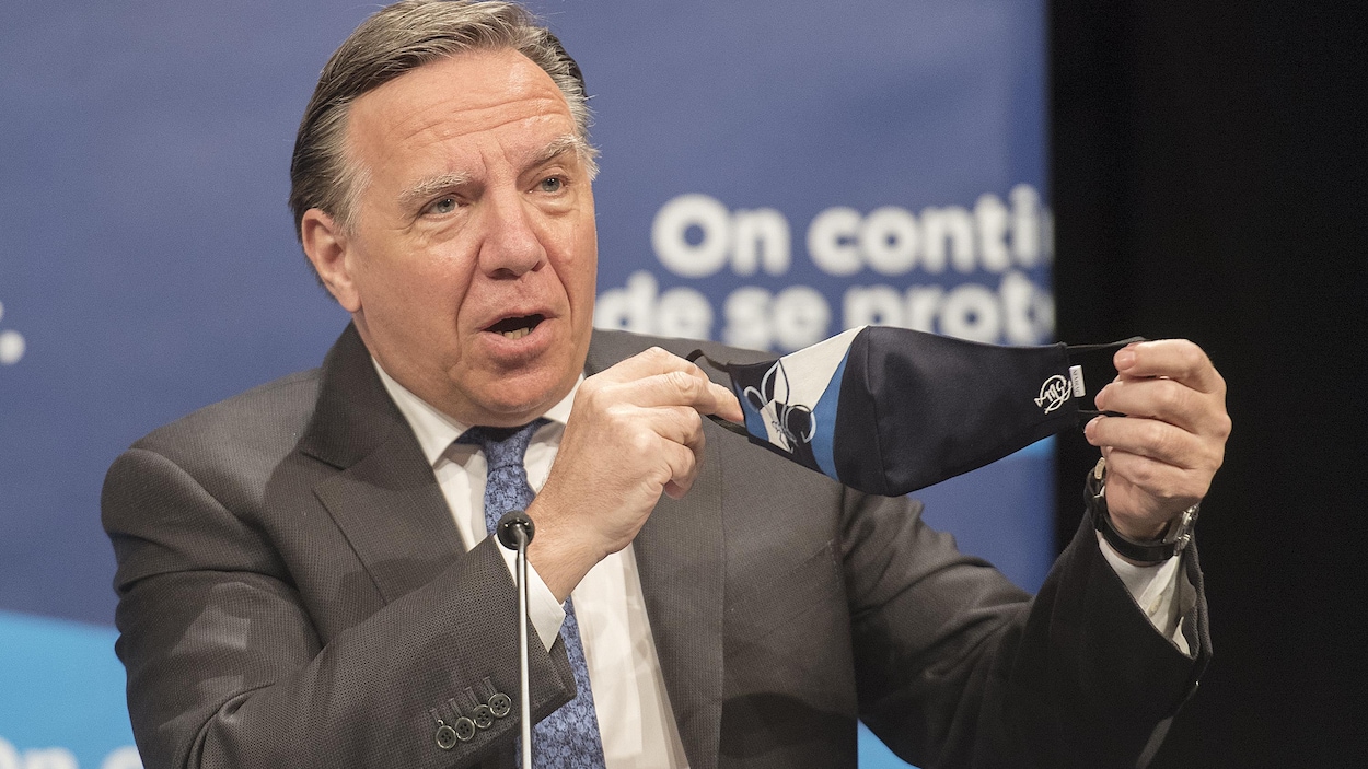 François Legault brandit un masque durant un point de presse.