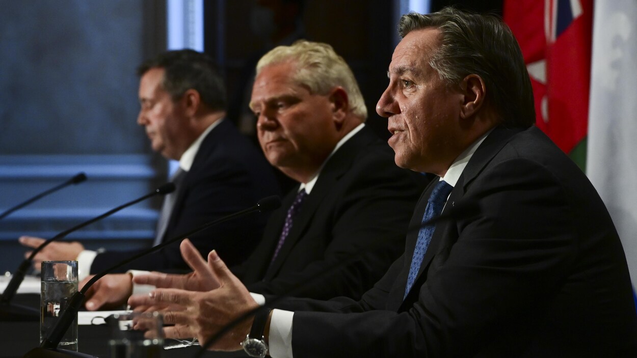 Jason Kenney, Doug Ford et Francois Legault assis en rangée à une table.