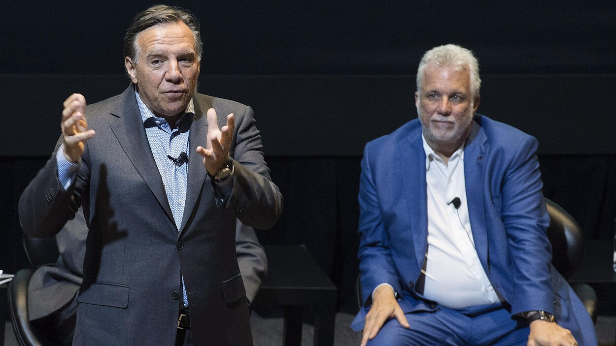 Le premier ministre Philippe Couillard écoute le chef de la CAQ, François Legault, lors d'un événement organisé par l'Institut du Nouveau Monde, le 17 août 2018. Le premier ministre Philippe Couillard écoute le chef de la CAQ, François Legault, lors d'un événement organisé par l'Institut du Nouveau Monde, le 17 août 2018.