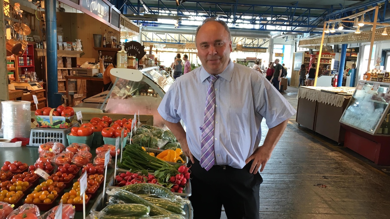 Monsieur Marchand debout près d'un étalage de légumes au Marché du Vieux-Port Monsieur Marchand debout près d'un étalage de légumes au Marché du Vieux-Port
