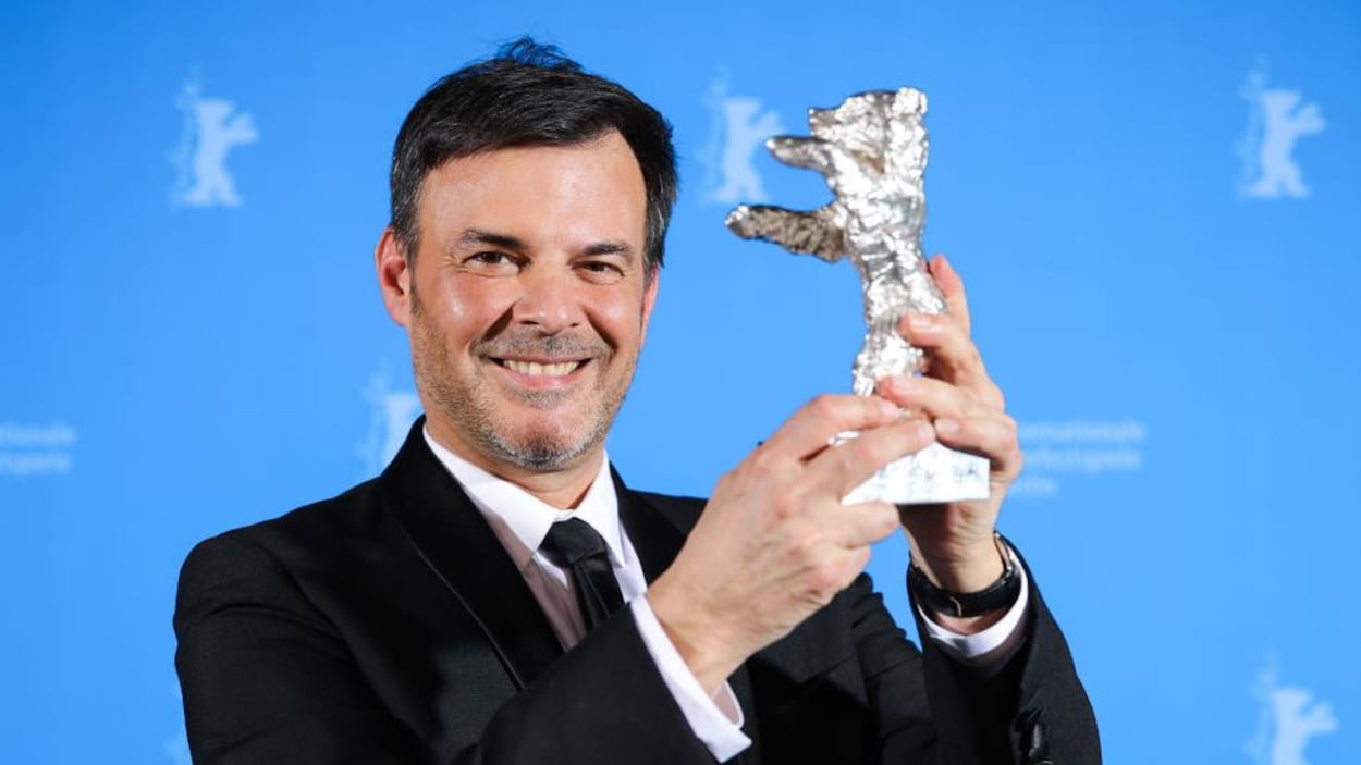 François Ozon tient une statuette en forme d'ours.