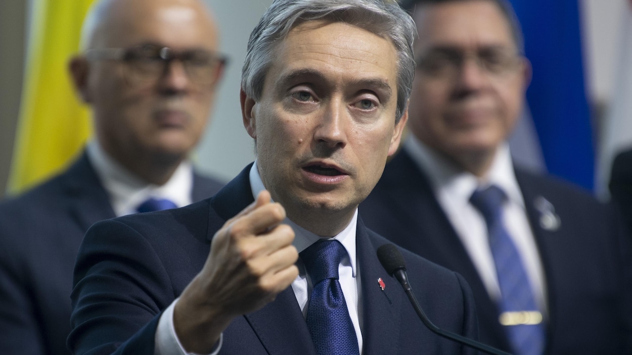Un homme parle et fait un geste de la main.