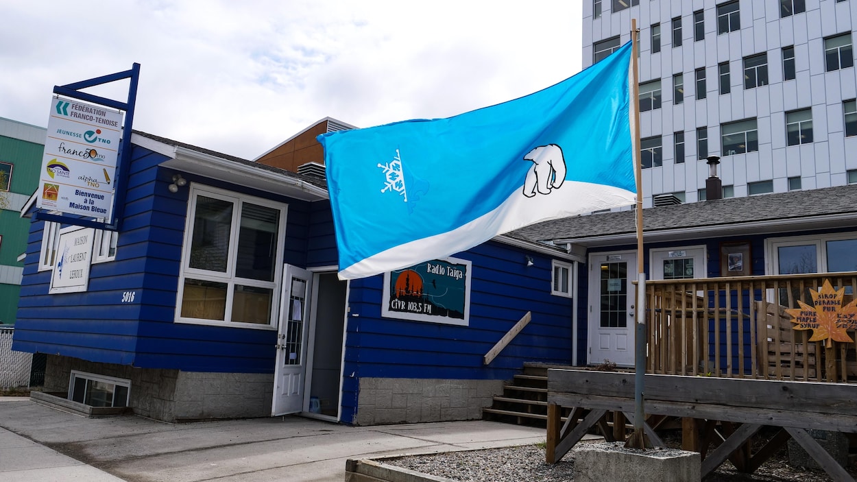 Un drapeau ténois flotte devant une maison bleue.