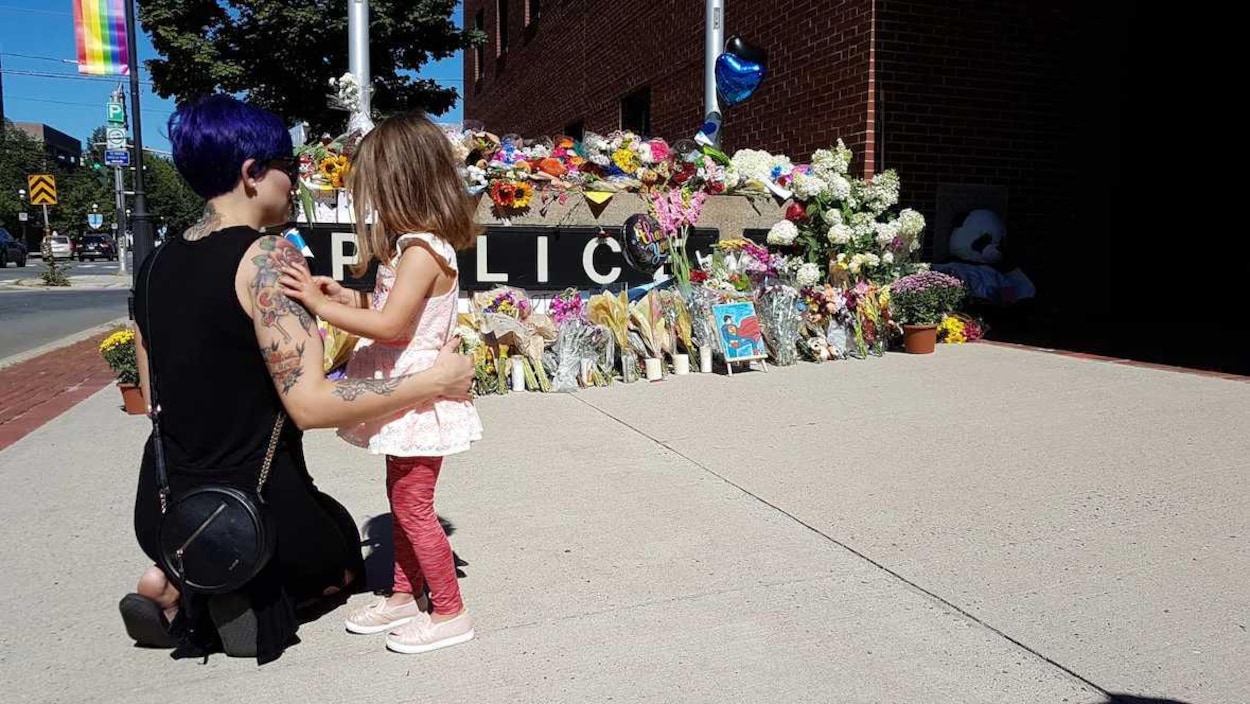 Une femme et une fillette observent un mémorial devant un poste de police à Fredericton le 11 août 2018. Une femme et une fillette observent un mémorial devant un poste de police à Fredericton le 11 août 2018.