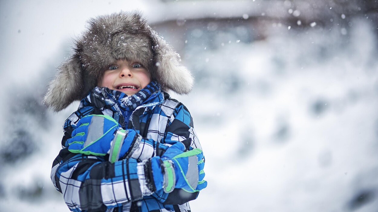 Un petit garçon dehors, un jour d'hiver.