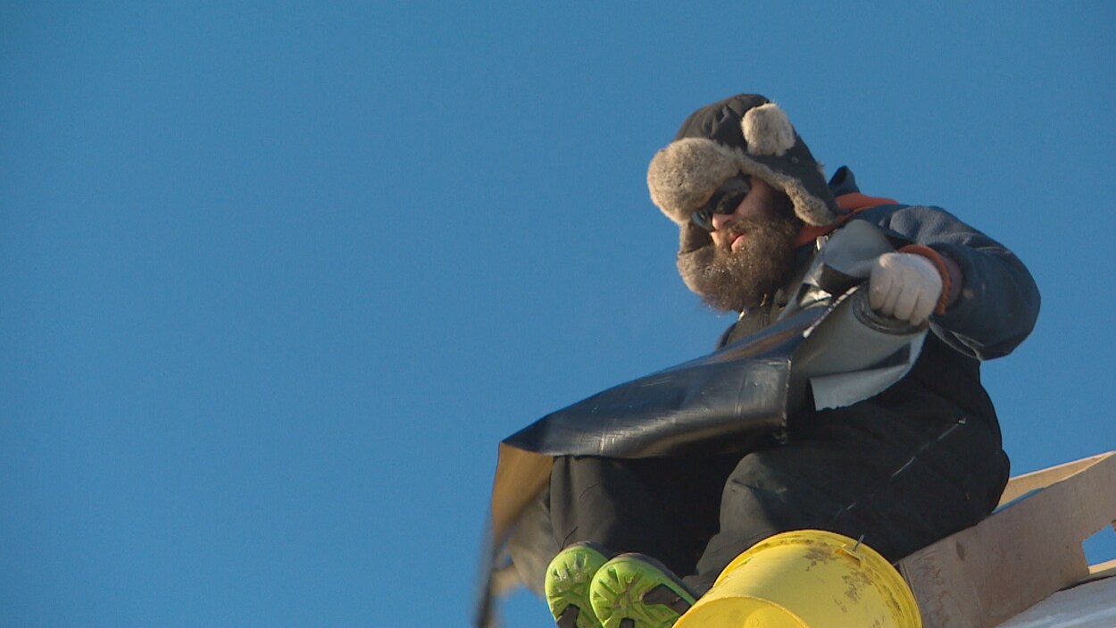 Samuel Cormier manipule de la membrane qu'il prévoit installer sur le toit d'une nouvelle maison en construction à Caraquet.