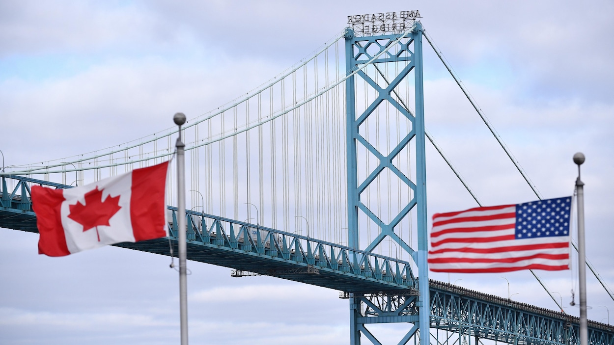 Les drapeaux canadien et américain qui flottent devant le pont Ambassador.
