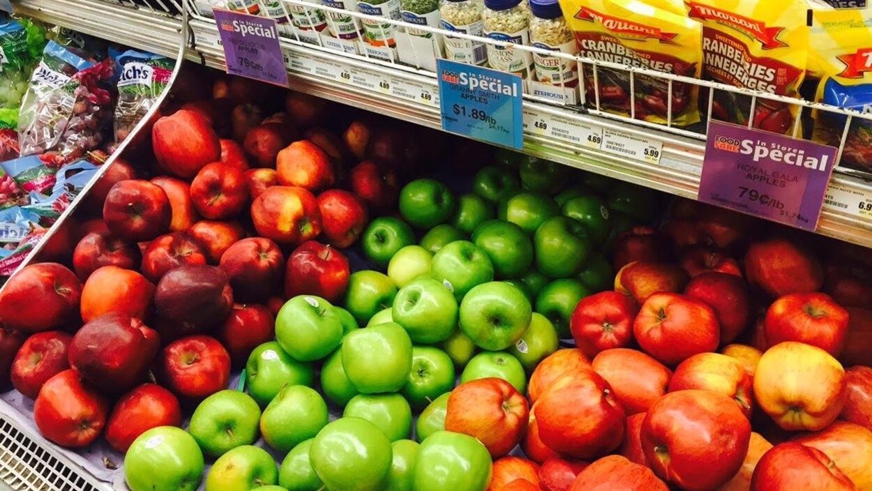 Des pommes affichées en solde dans un présentoir.