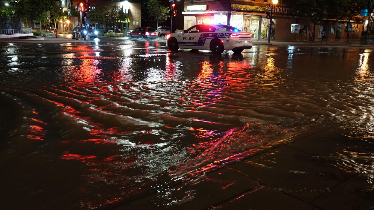 Une rue inondée avec une voiture de police.