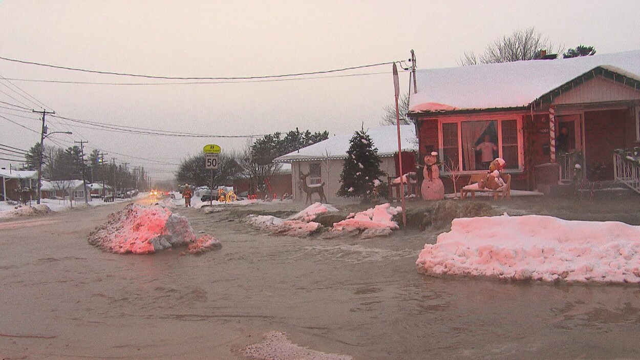 De l'eau s'écoule en grande quantité dans une rue et sur le terrain d'une résidence unifamiliale. De l'eau s'écoule en grande quantité dans une rue et sur le terrain d'une résidence unifamiliale.