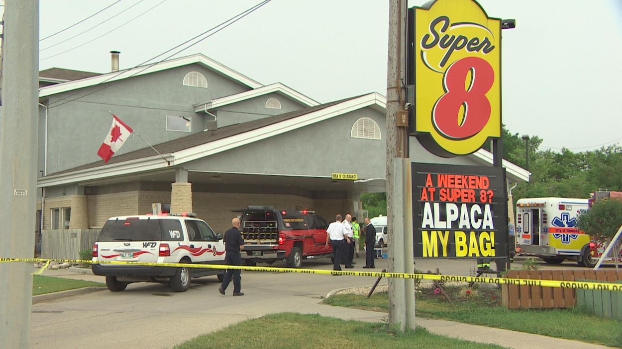 Des véhicules d'urgence et des membres de l'équipe de secours devant un motel Super 8.