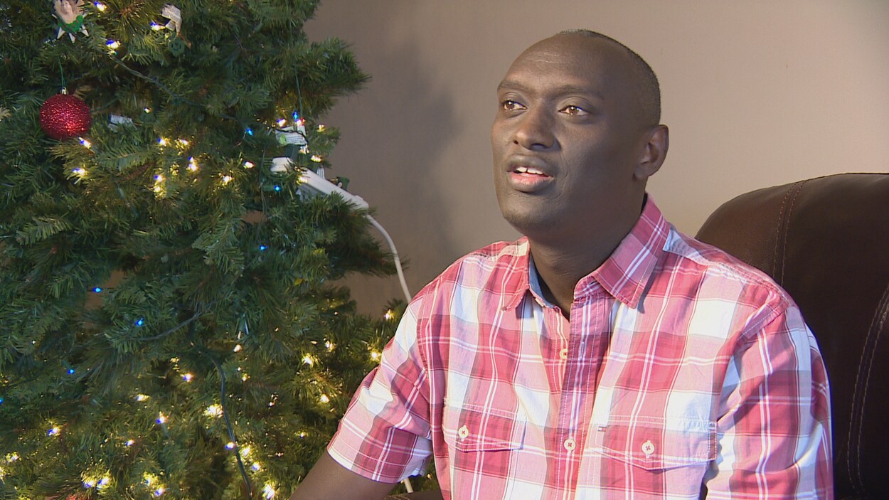 Fulgence Ndagijimana dans son salon près de son sapin de Noël.