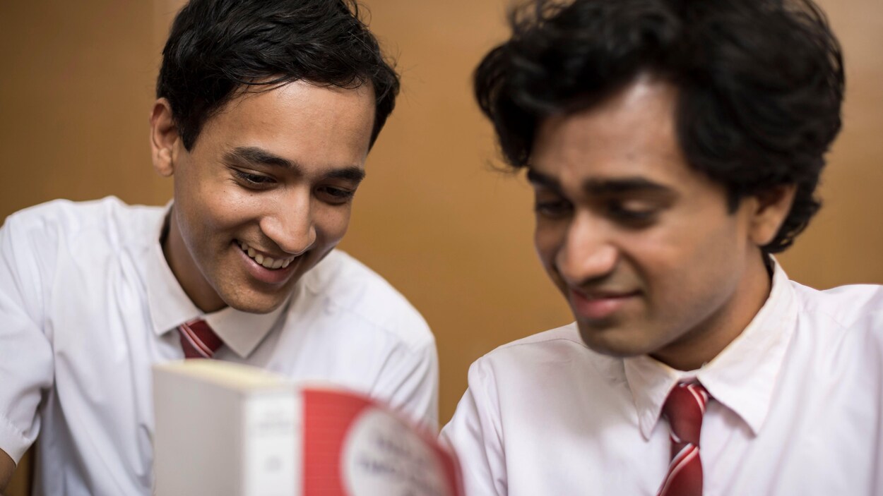 Deux jeunes hommes regardent un livre.