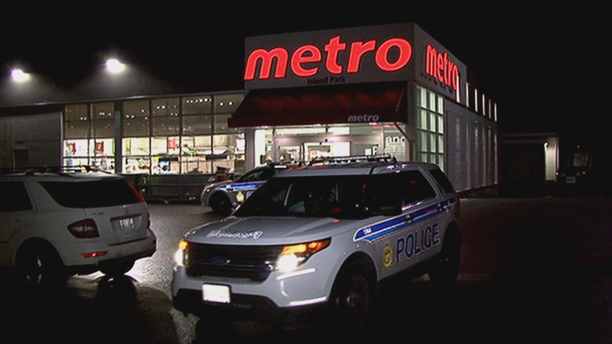 Deux véhicules de police se trouvent devant l'épicerie Metro Island Park.