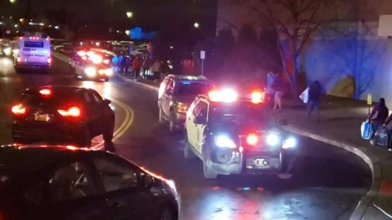 Des voitures de police à proximité d'un centre commercial, le soir.