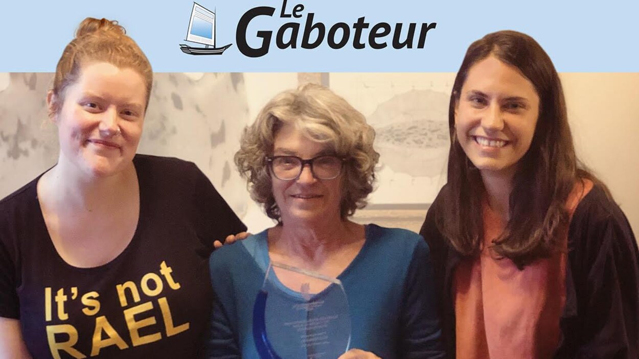 Trois femmes tiennent un trophée.
