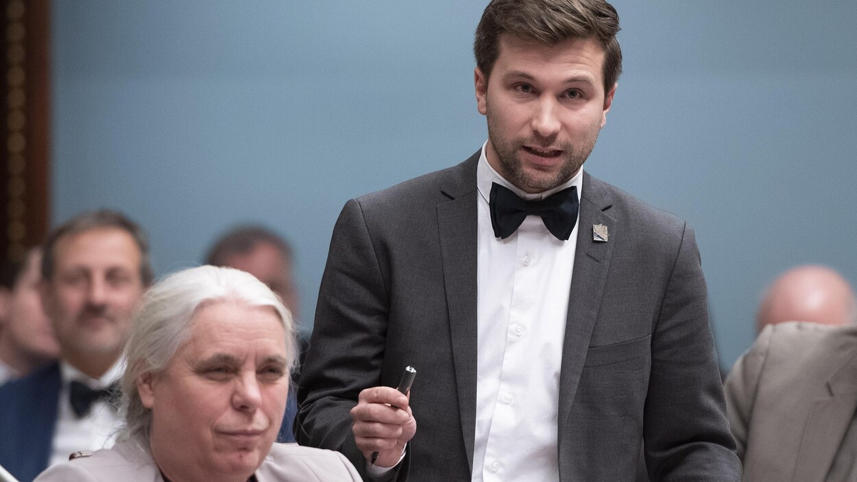 Gabriel Nadeau-Dubois debout à l'Assemblée nationale du Québec aux côtés de Manon Massé, assise.