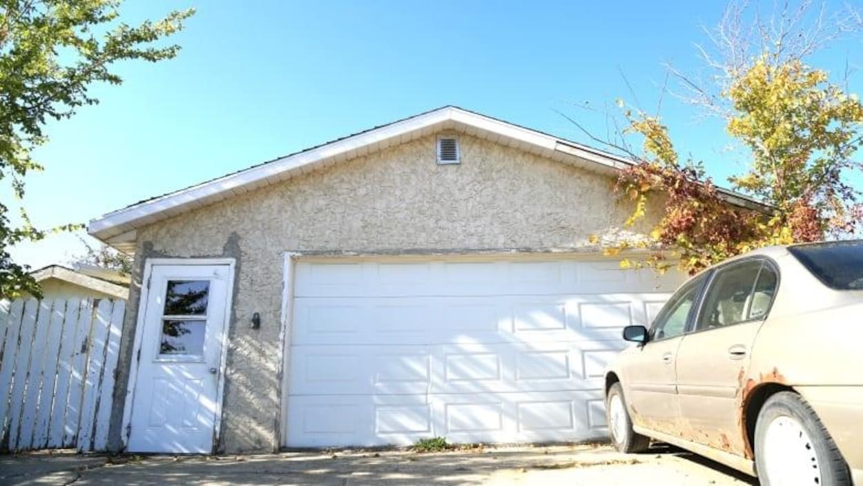 Vue extérieure du garage avec une voiture stationnée dans l'entrée.