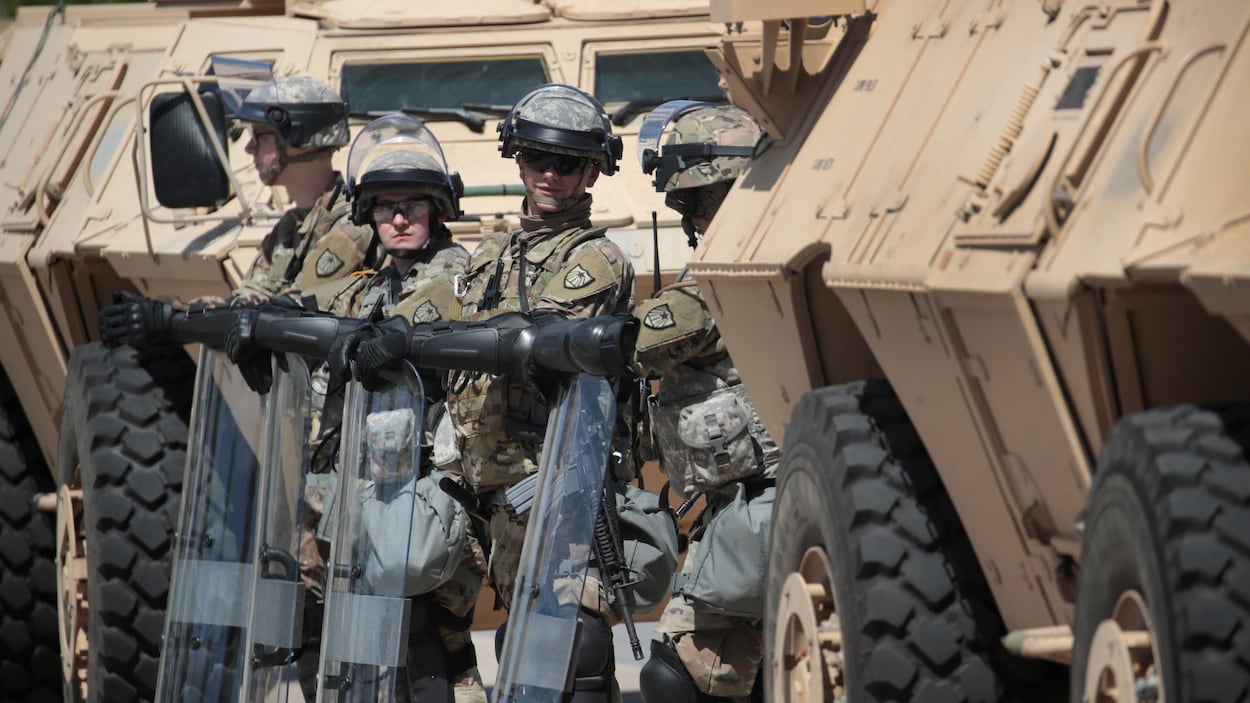 Des militaires de la garde nationale, en poste entre deux véhicules blindés.