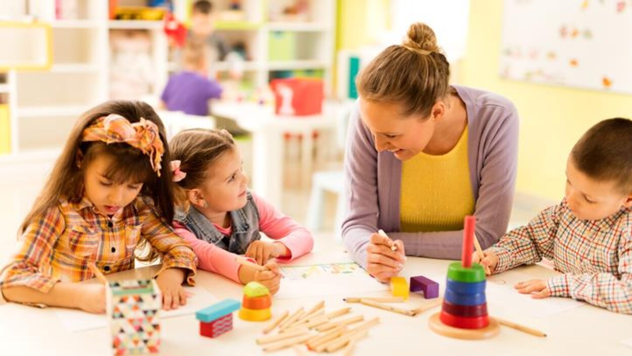Une jeune femme dessine avec des enfants dans une salle de classe.