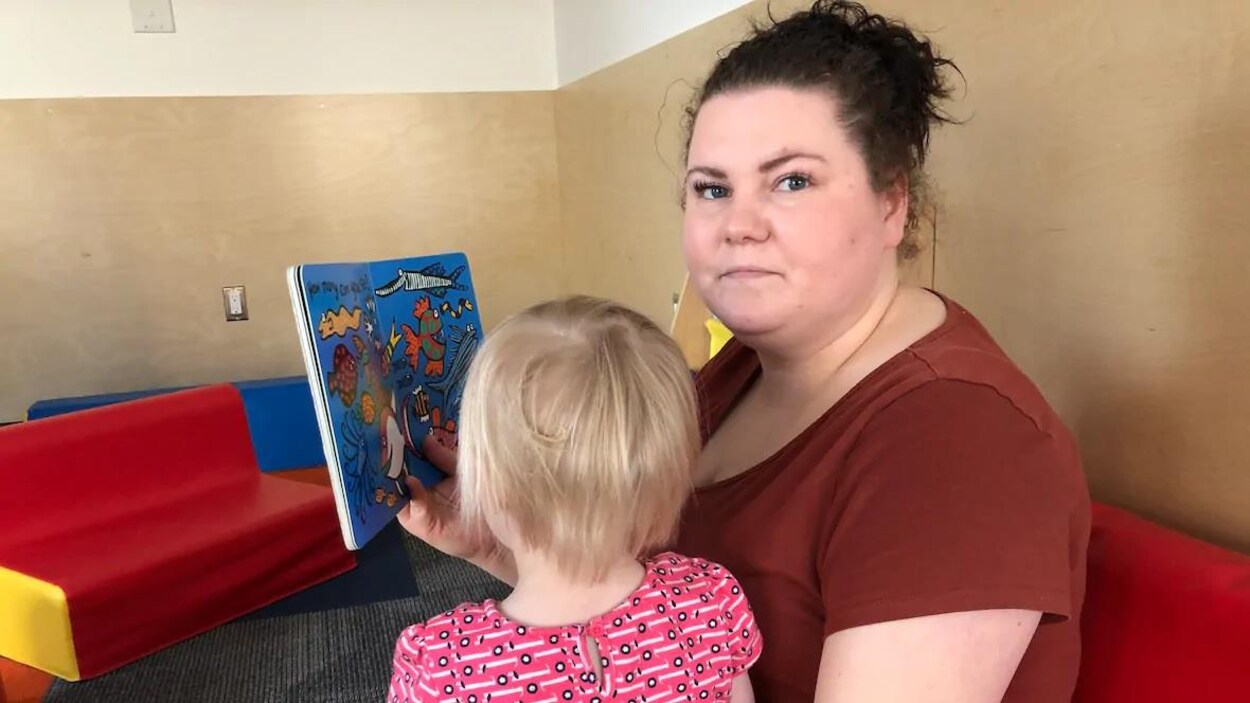 Sondra Marsh montre un livre à une petite fille assise sur ses genoux.