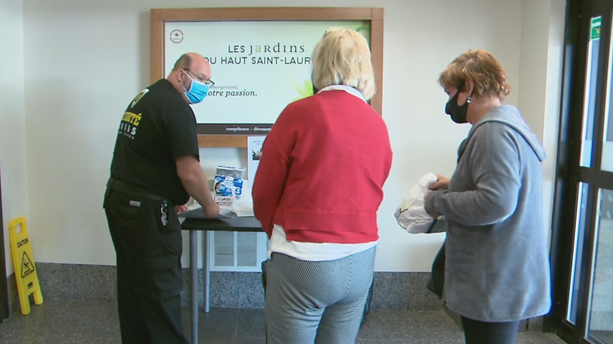 Un gardien de sécurité accueille deux dames à l'entrée de la résidence.