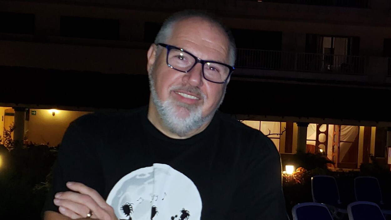 Les bras croisés, M. Lavigne pose en souriant.