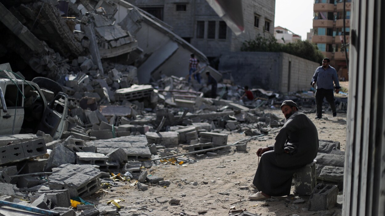 Un homme est assis sur des débris à Gaza.
