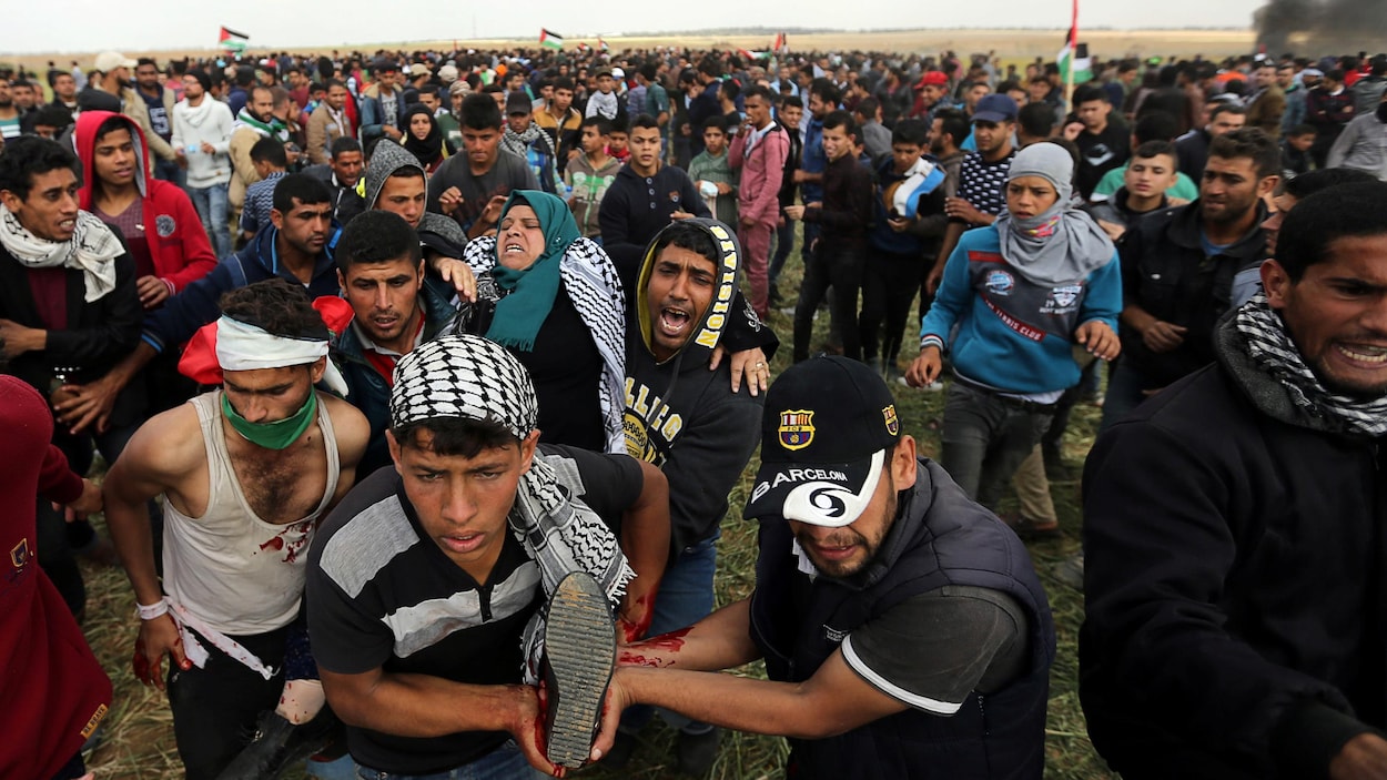 Une Palestinienne blessée est emportée par un groupe d'hommes à travers la foule.