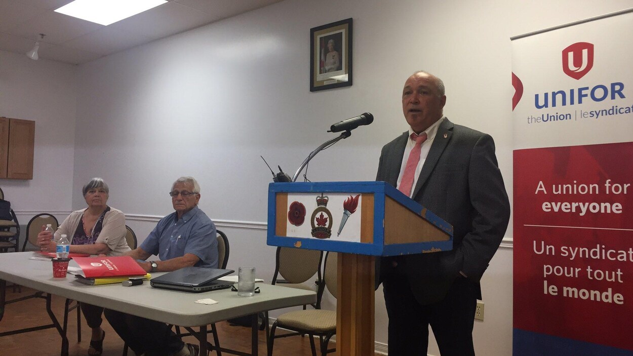 Trois personnes lors d'une présentation avec un panneau du syndicat Unifor Trois personnes lors d'une présentation avec un panneau du syndicat Unifor