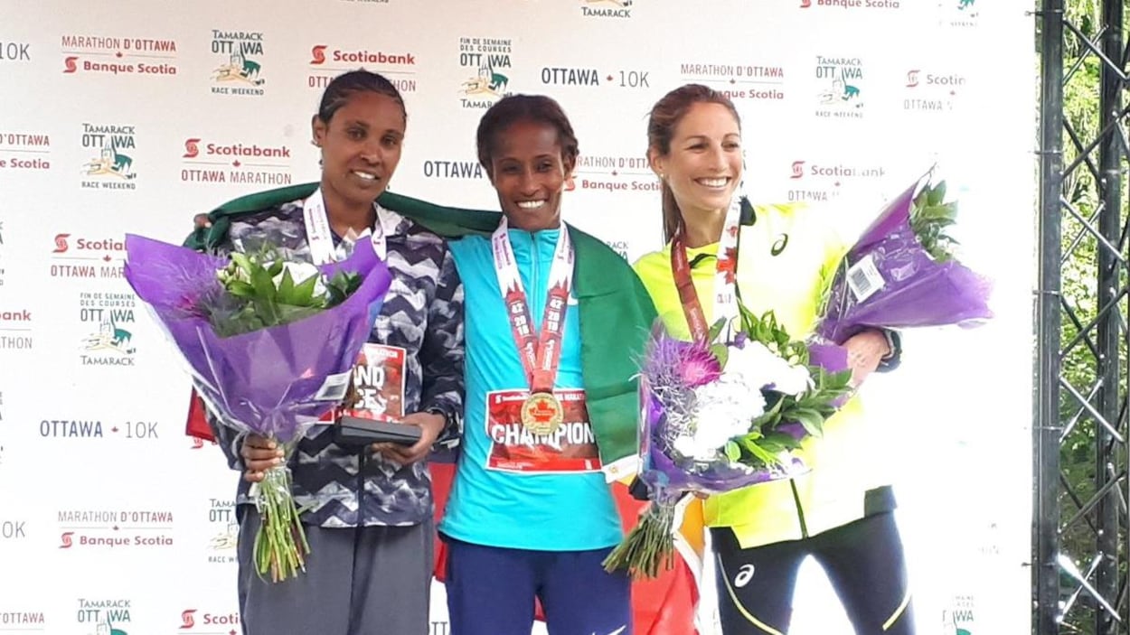 Trois femmes avec des médailles et des bouquets de fleurs.