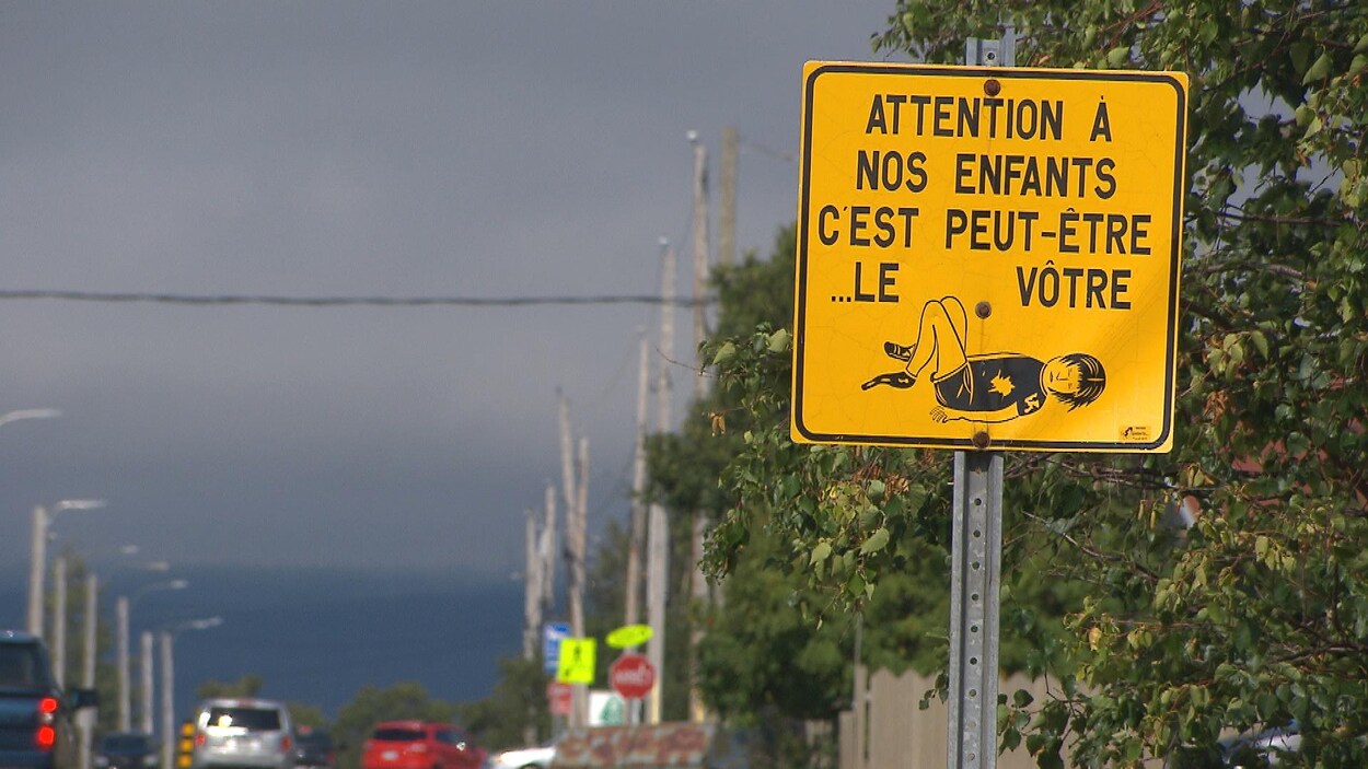 Une pancarte jaune sur laquelle il est inscrit "attention à nos enfants c'est peut-être... le vôtre".