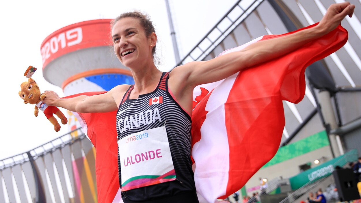 Geneviève Lalonde avec le drapeau du Canada et une peluche de la mascotte des Jeux panaméricains après sa victoire au 3000 m steeple