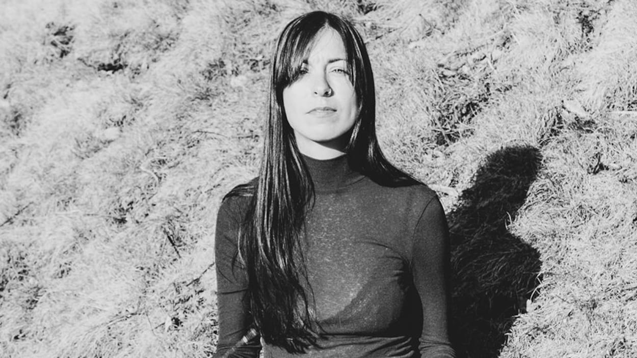 Une photo en noir et blanc de Geneviève Toupin assise dans le gazon.
