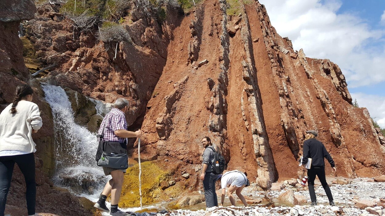 Des guides en formation devant la formation rocheuse qui montre que le terrain ea subi de puissantes transformations, passant de l'horizontale à la verticale.