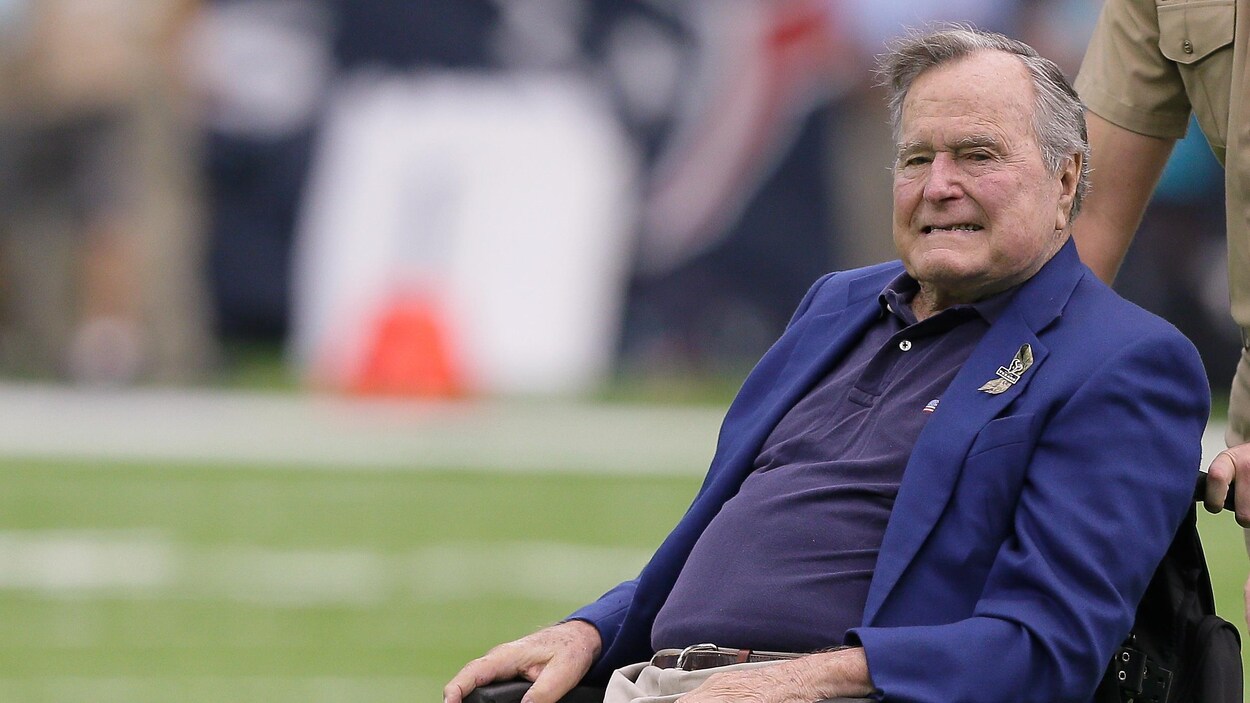George H.W. Bush est assis dans une chaise roulante sur un terrain de football. George H.W. Bush est assis dans une chaise roulante sur un terrain de football.