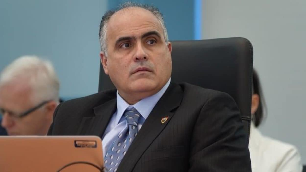 George Darouze assis dans une salle devant un ordinateur portable.